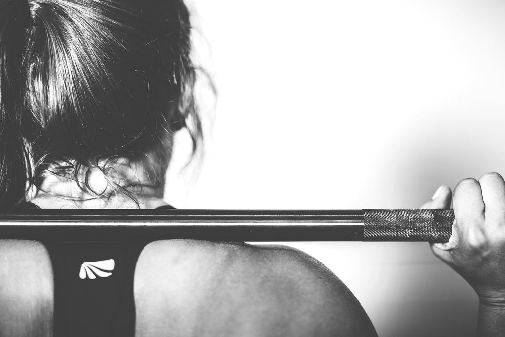 Black and white photo of a woman doing a squat with a barbell on her shoulders 